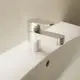 Waschtischarmatur aus Chrom mit einem flachen Hebel und Auslauf, montiert auf einer weißen Ablage, vor einer neutralen Wand. Ideal Standard.